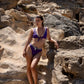 Woman in a purple bikini standing on rocky terrain